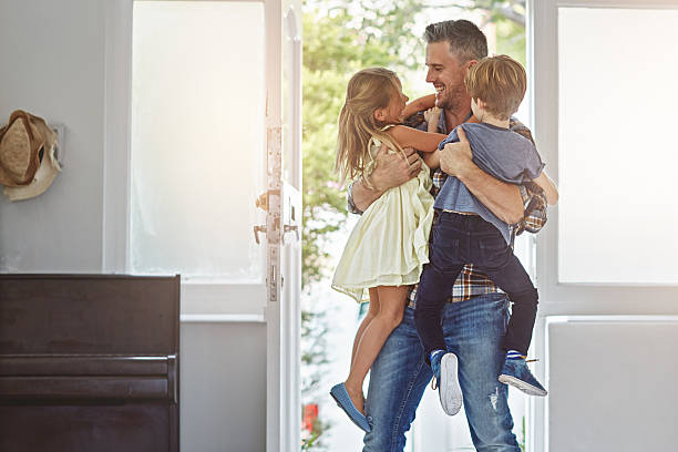 How was your day daddy? Shot of a father embracing his two children as he enters the house lens flare offspring daughter human age stock pictures, royalty-free photos & images