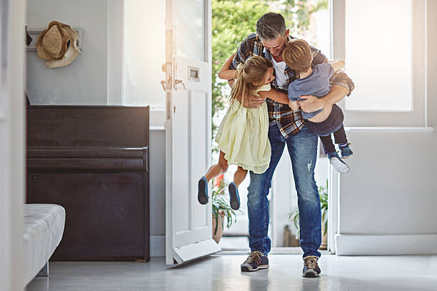 Shot of a father embracing his two children as he enters the house