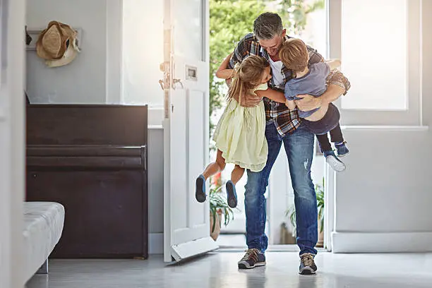 Shot of a father embracing his two children as he enters the house