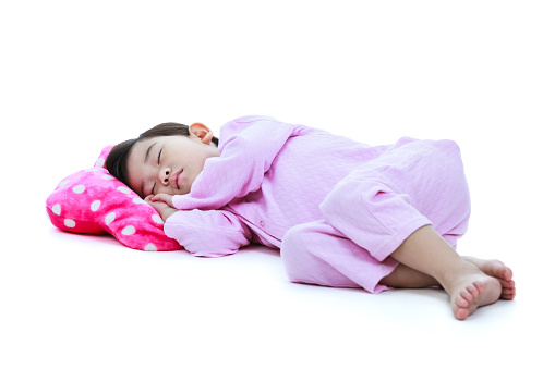 Full body. Healthy children concept. Asian child sleeping peacefully. Adorable girl in pink pajamas taking a nap. Isolated on white background.