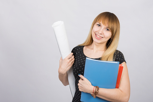 Girl student smiling and holding blueprints and a folder with documents