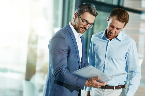 Shot of two businessmen talking over some paperwork in an office