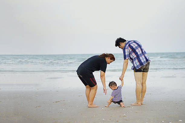 istock Happy Young Asian Family Having Fun Walking on beach 540526632