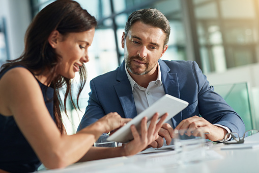 Shot of two businesspeople using a digital tablet together in an office