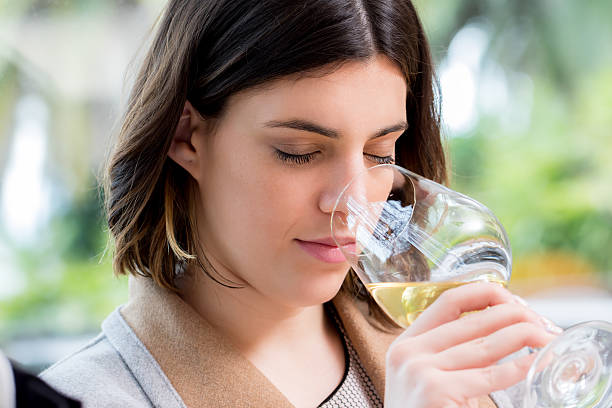Young woman smelling white wine at tasting.