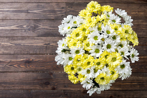 Yellow flowers of a chrysanthemum with gift bag and seashell, selective focus. Still life on a wooden background with copy space for text