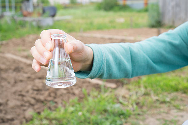 mão com um tubo de ensaio e instalação. adubo em laboratório - groundwater imagens e fotografias de stock