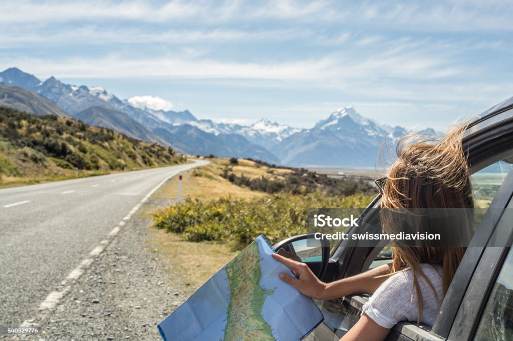 Portrait of young woman in car looking at map Portrait of a young woman in a car looking at a map for directions. Car Stock Photo