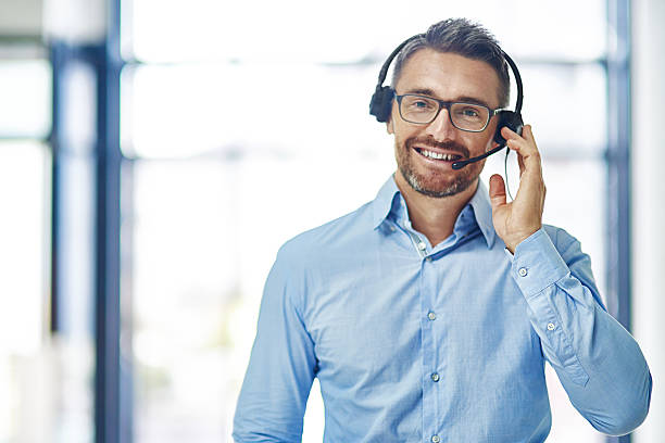 Let’s talk Portrait of a friendly mature businessman wearing a headset in an office headset stock pictures, royalty-free photos & images