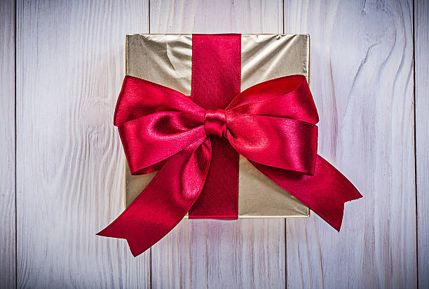 istock Giftbox in glittery paper with red bow on wood board 540566954