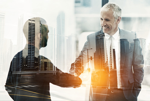 Multiple exposure shot of two businesspeople shaking hands superimposed on a cityscape