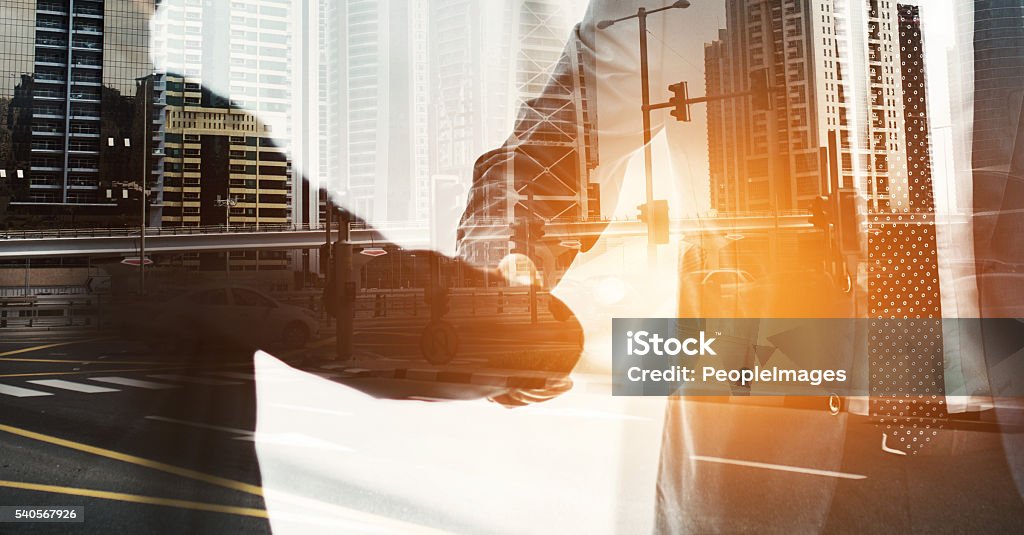 City deals in the making Multiple exposure shot of two businesspeople shaking hands superimposed on a cityscape Mergers and Acquisitions Stock Photo