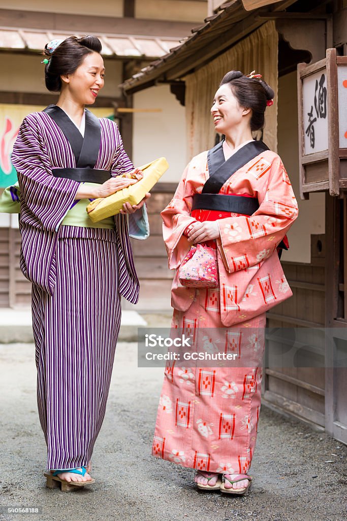 Meeting After a Long Time Japanese women wearing traditional Kimono & Geta, walking along the village neighborhood. Geta Sandal Stock Photo