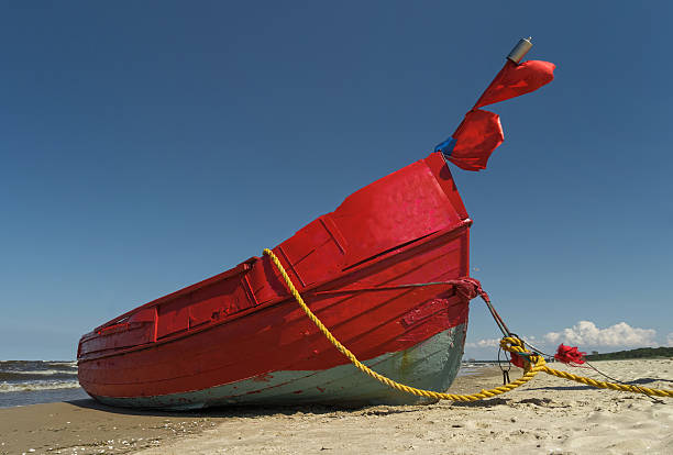 istock Red Fishing Boat in sunlight on sand beach 540568616