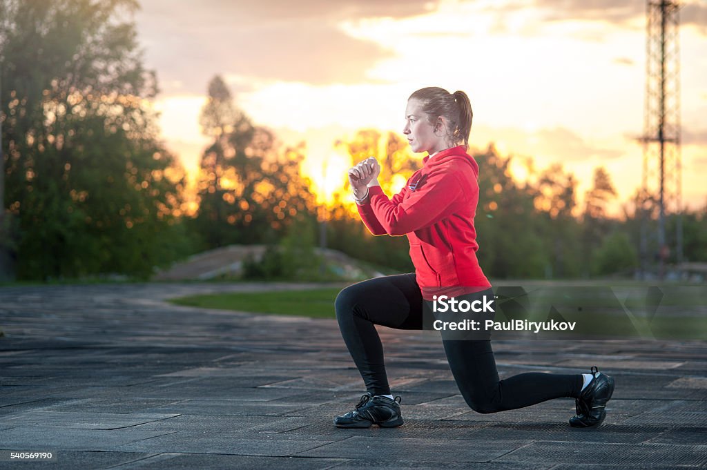 Woman in sportswear doing squats outdoors Fit woman in sportswear doing frontal lunges (squats). Fitness, workout, sport outdoors concept. Only Women Stock Photo