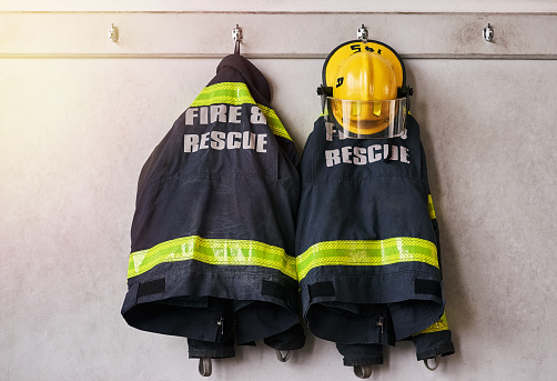 Cropped shot of firemen's clothing hanging from a wall