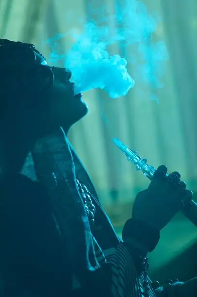 girl let the smoke from a hookah in blue light