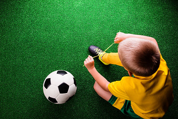 istock Unrecognizable little football player against green grass, studi 540571306