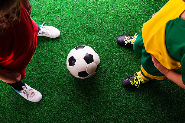 zwei nicht erkennbare kleine fußballer gegen grünes gras - soccer child indoors little boys stock-fotos und bilder