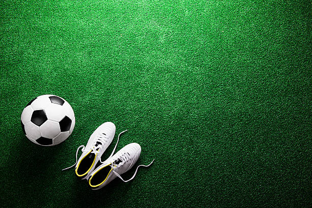 balón de fútbol y grapas contra verde césped artificial, ducha tipo estudio - botas de fútbol fotografías e imágenes de stock