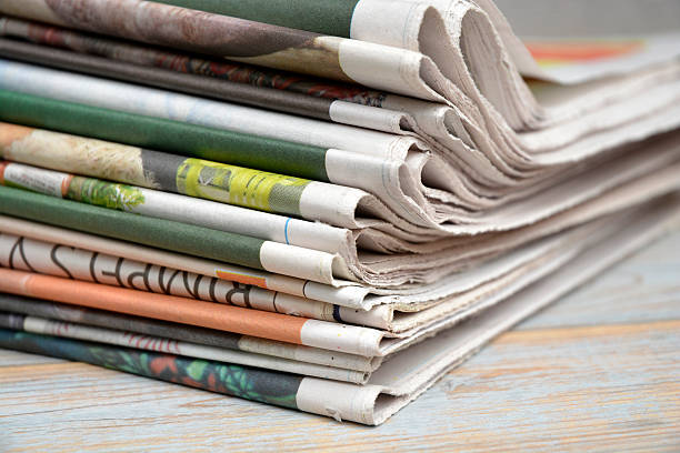 istock Close up  folded stacked color newspapers on wooden table background 540573162
