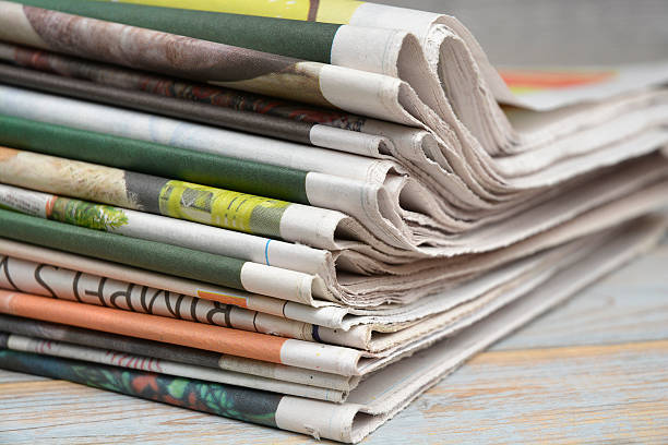 istock Close up  folded stacked color newspapers on wooden table background 540573266