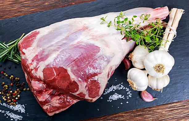 Raw lamb leg on blue stone background with herbs Raw lamb leg on blue stone background with herbs. lamb meat photos stock pictures, royalty-free photos & images