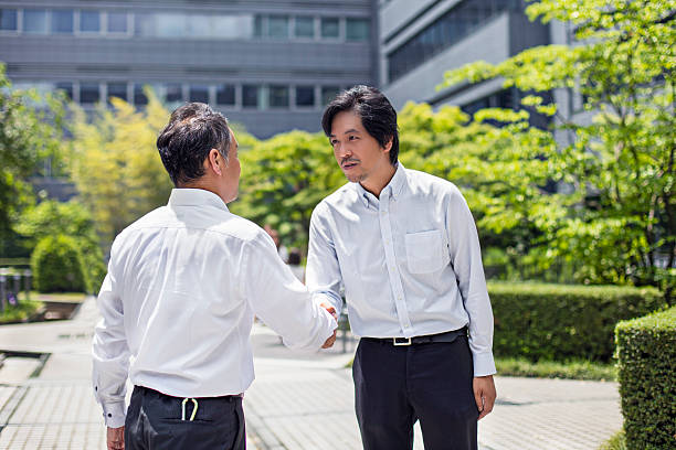 dwa biznesmeni uścisk dłoni na świeżym powietrzu japoński - handshake respect japan business zdjęcia i obrazy z banku zdjęć