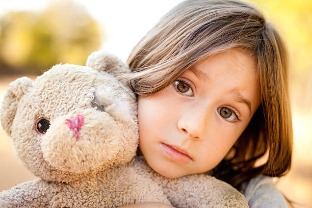 istock Sad Little Girl Hugging Old, Ragged Teddy Bear Outside 540586662
