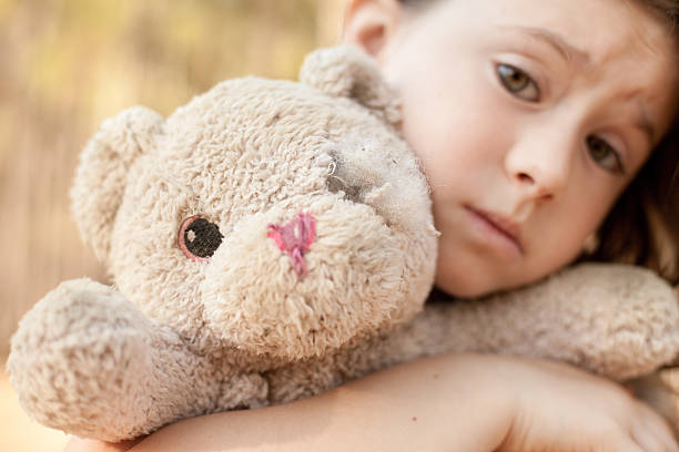 Pensive sad little girl with his teddy bear friend at home  on sunset, nice soft  light, haze filter