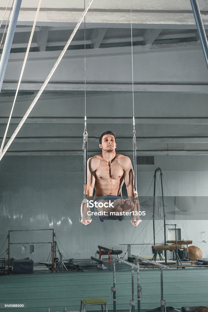 Gymnast on Stationary Rings The sportsman performing difficult exercises on on stationary rings, sports gymnastics Active Lifestyle Stock Photo