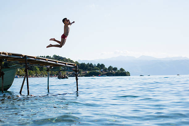 istock Young boy jumping into lake 540589440