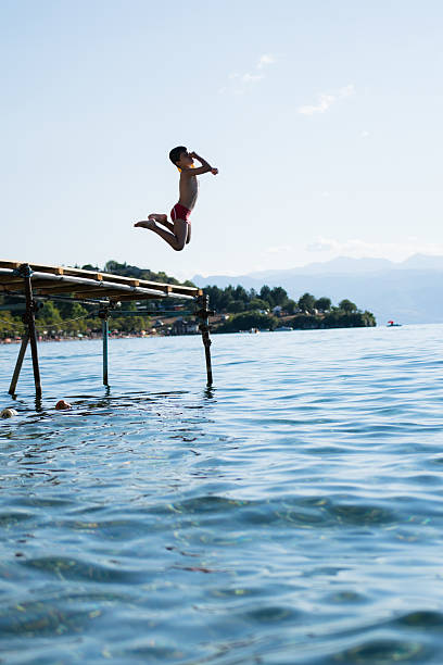 istock Young boy jumping into lake 540589578