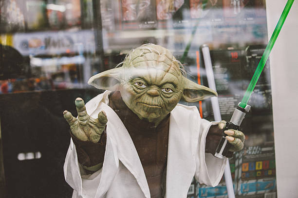 Master Yoda Paris, France - April 28, 2016: Portrait of Jedi Master Yoda toy model with green lightsaber on window display in Paris. Yoda is a fictional character in the Legend Star Wars Film franchise created by director George Lucas star wars stock pictures, royalty-free photos & images