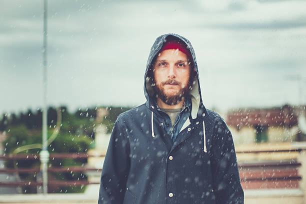Man with raincoat under heavy rain Man with raincoat under heavy rain raincoat stock pictures, royalty-free photos & images