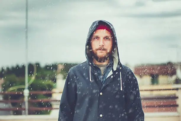 Man with raincoat under heavy rain