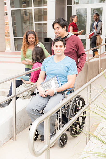 istock Education: Disabled student helped down wheelchair ramp. College campus. 540598380
