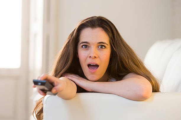 istock young  woman on couch holding remote control watching television happy 540602098