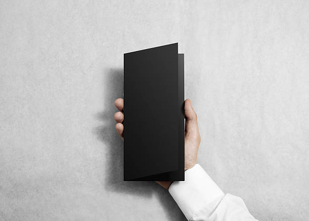 istock Hand holding blank black opened brochure booklet. 540609758