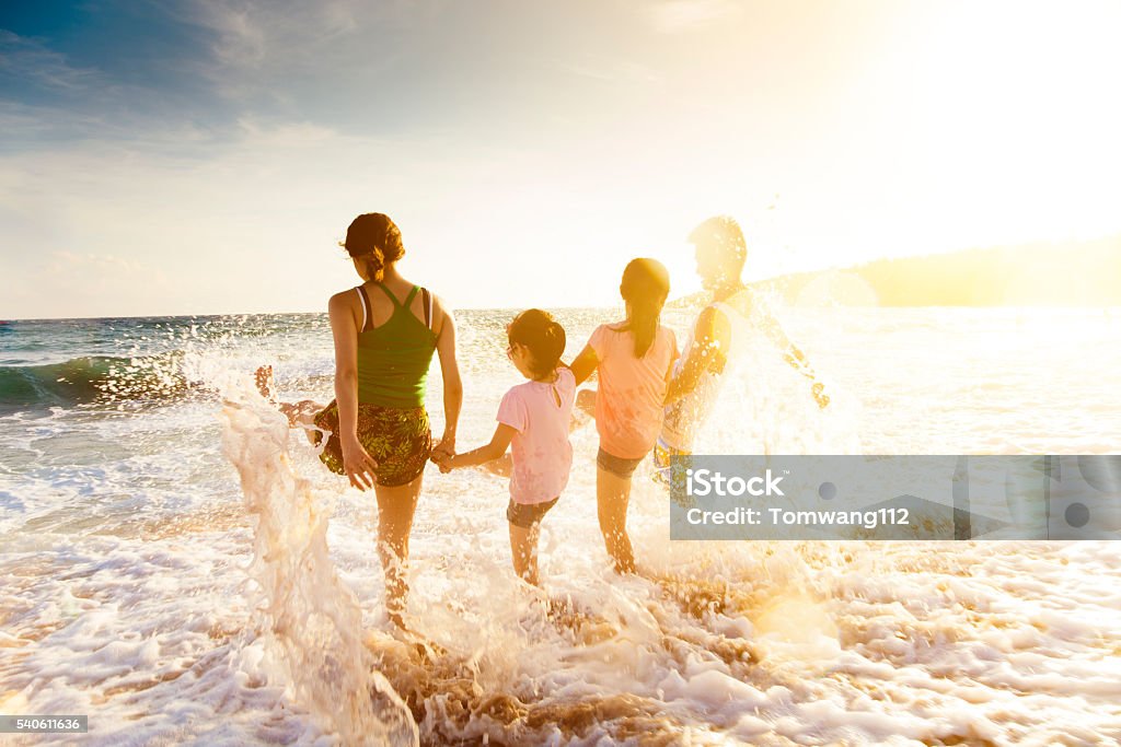 happy young family playing on beach at sunset Family Stock Photo