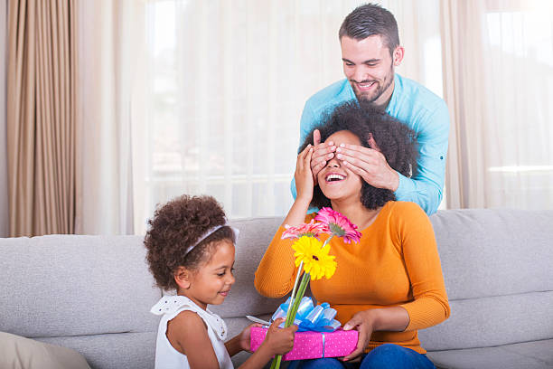 figlia tiene regalo e fiori, padre con madri gli occhi - men african descent giving flower foto e immagini stock