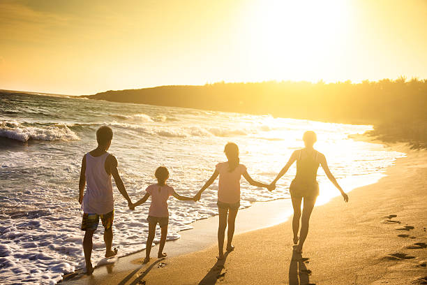 istock happy young family walking on beach at sunset 540612078
