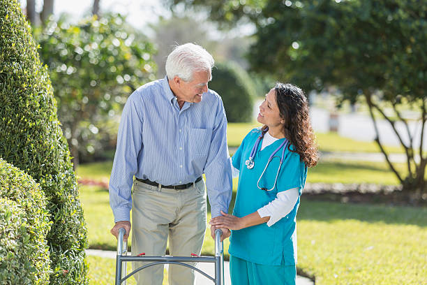 istock Female nurse helping senior man using walker outdoors 540716996