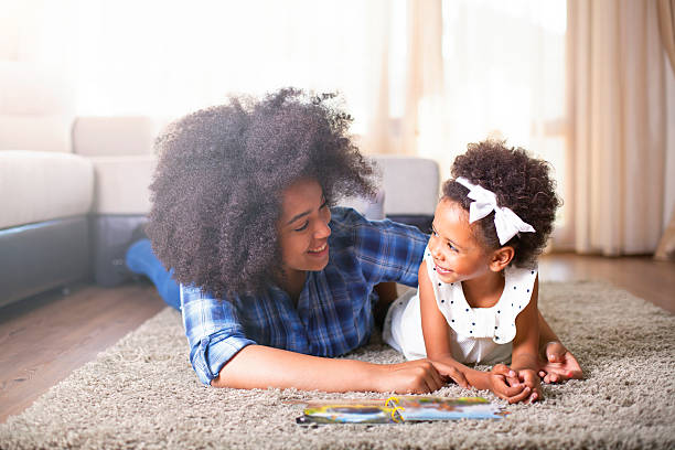 istock Mother reading a book to her daughter on carpet 540717002