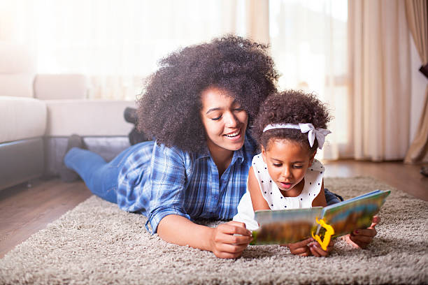 Mother reading a book to her daughter on carpet