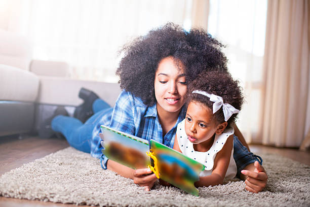 istock Mother reading a book to her daughter on carpet 540717056