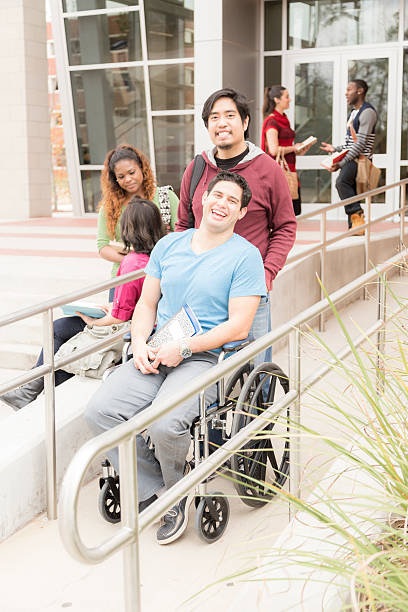 istock Education: Disabled student helped down wheelchair ramp. College campus. 540717582