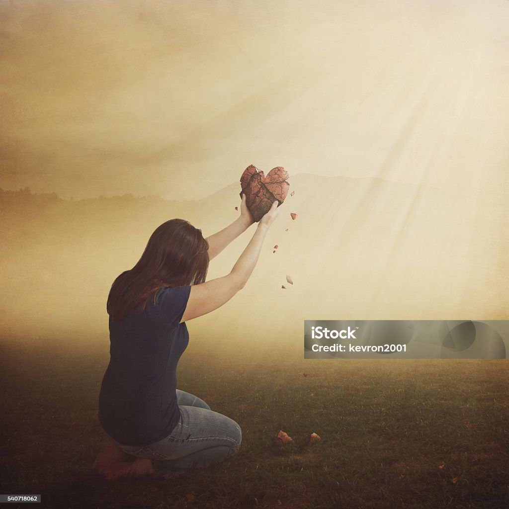 Woman with broken heart. A woman with a broken heart in field. Heart Shape Stock Photo