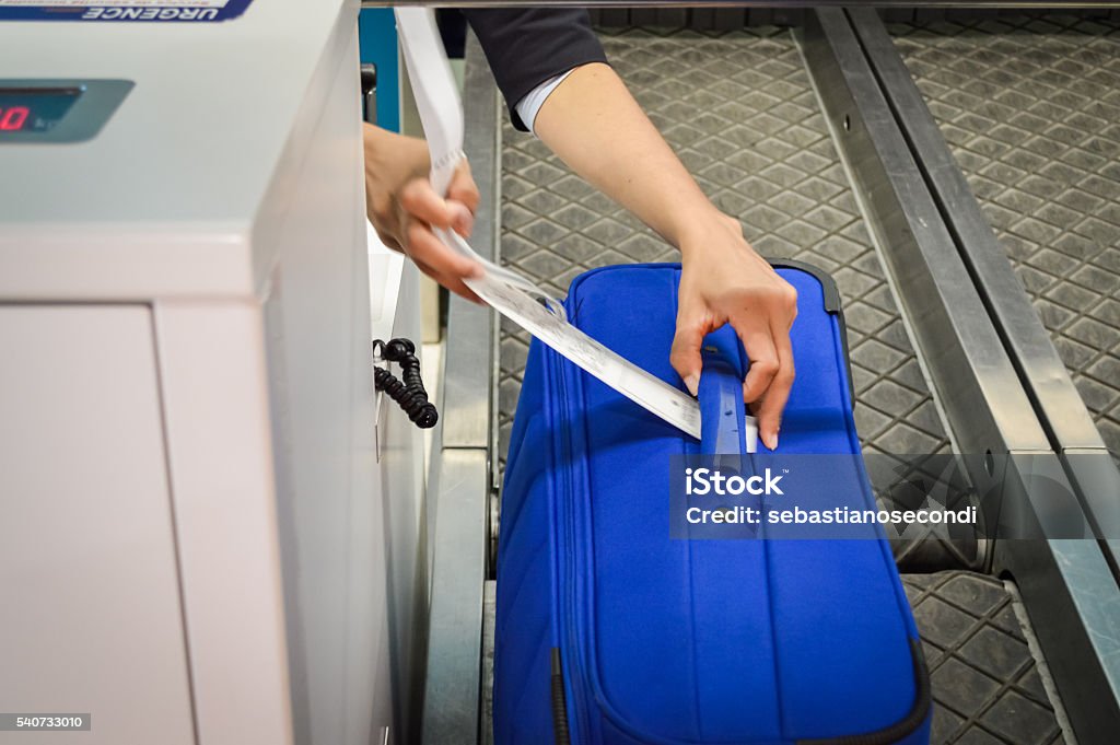 hands attaches a luggage tag to suitcase check-in employee attaches a luggage tag to suitcase of passenger - close up of hands Airport Check-in Counter Stock Photo