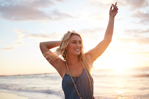 Portrait of attractive young woman enjoying on the beach at sunset. Caucasian female model having fun on the sea shore.